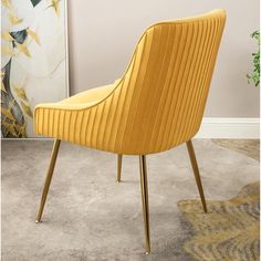 a yellow chair sitting on top of a carpeted floor next to a wall mounted painting