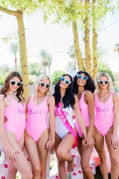 four women in pink bathing suits posing for a photo with palm trees behind them and the words babe on their chest