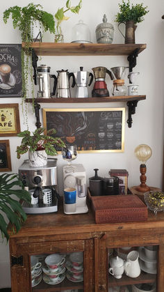 a coffee bar with lots of cups and saucers on the shelves above it is filled with plants