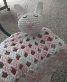 a crocheted bunny sitting on top of a blanket in the middle of a room