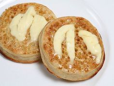 two pancakes on a white plate topped with butter