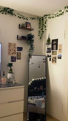 a living room with a refrigerator and some plants on the wall next to an entertainment center