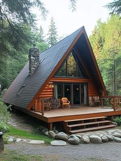 a small cabin in the woods with a deck and chairs on it's front porch