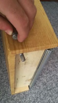 a person is using a mouse to push the latch on a wooden object