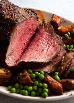 a close up of a plate of food with meat and vegetables on it, including peas