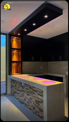 an empty kitchen with black cabinets and stone counter tops is pictured in this image, there are lights above the bar