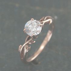 a close up view of a ring with a diamond in the center and vines on it