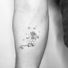 a man's leg with a small astronaut tattoo on the left side of his arm