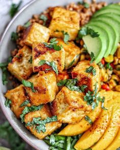 a bowl filled with tofu, rice and avocado on top of a table