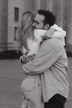 a man and woman embracing each other in front of a building