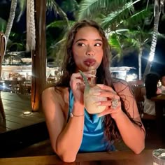 a woman sitting at a table with a drink in her hand