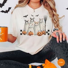 This adorable shirt is perfect for Halloween season! 💕 The Comfort Colors t-shirts are made of high-quality cotton and come in various sizes and colors. 💕 If you have any questions or requests, please feel free to contact us. We hope you enjoy browsing our shop and find something you love! 💕 FEATURES: - Sizes offered: Please see the sizes we offer per the dropdown menu - Colors: Please see the dropdown menu and photos - Material: 100% Garment-dyed soft ring spun fabric - Style: Short Sleeve Unisex T-Shirt - Care: Machine wash cold, delicate inside out with like colors. Tumble dry low or hang to dry. Do not bleach, do not dry clean. Do not iron directly on the print. - Graphic is professionally DTF ("direct to transfer") printed using leading industry equipment. 💕 SIZE/FIT: - For an ove White T-shirt With Cat Design For Fall, Fall Cat Design Short Sleeve T-shirt, Kawaii Halloween Short Sleeve T-shirt, Halloween White T-shirt With Cat Print, Halloween Cat Print Crew Neck T-shirt, Cat Lover Shirt, Ghost Cat, Ghost Shirt, Cute Ghost