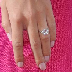 a woman's hand with a diamond ring on her left hand and pink background