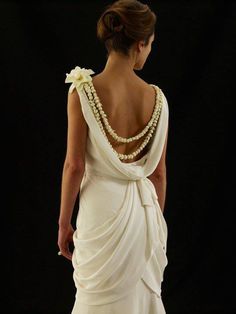 a woman in a white dress with pearls on her back