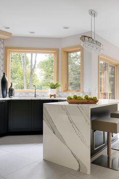 a modern kitchen with marble counter tops and black cabinets, along with an island in the middle