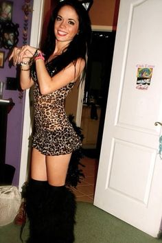 a woman in leopard print dress and black boots posing for the camera with cat ears on her head