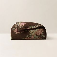 a brown floral print bag sitting on top of a white table