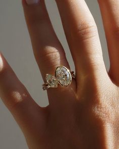 a woman's hand with a diamond ring on top of her finger and the other hand holding an engagement ring