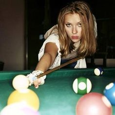 a young woman leaning over a pool table