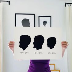 a woman holding up a poster with silhouettes of people's heads