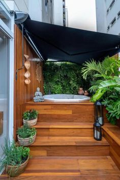 an outdoor jacuzzi with plants and potted plants on the steps in front of it