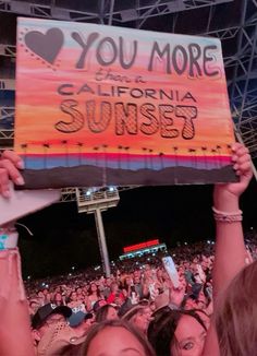 two girls holding up a sign that says you're more california sunset at a concert