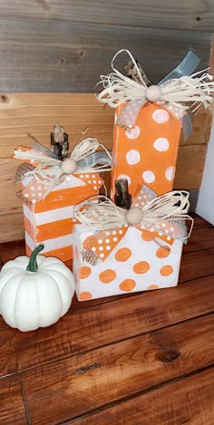 three small boxes with polka dots and pumpkins on the top are sitting on a wooden table