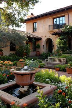 a fountain in the middle of a garden with potted plants and flowers around it