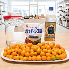 oranges and water on a table in front of a glass jar with chinese writing