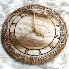 a clock that is on top of a white fur rug with gold numbers and roman numerals