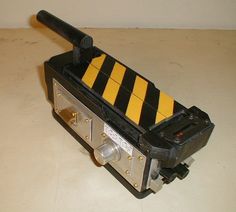 a black and yellow device sitting on top of a white table next to a wall