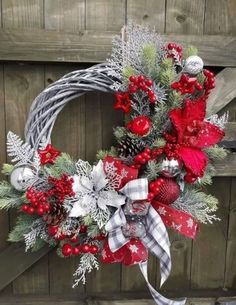 a christmas wreath hanging on the side of a wooden door with red and silver decorations