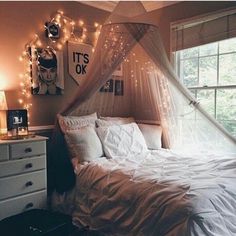 a white bed sitting in a bedroom next to a window with string lights on it