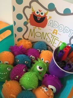 there are many toys in the bowl on the table with a sign above it that says adopt a monster