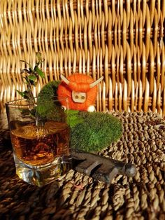 an orange stuffed animal sitting on top of a table next to a glass filled with liquid