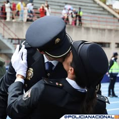 two police officers kissing each other in front of some people on a tennis court with their backs to one another