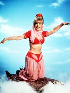 a woman in a pink outfit on top of a rock with her arms spread out