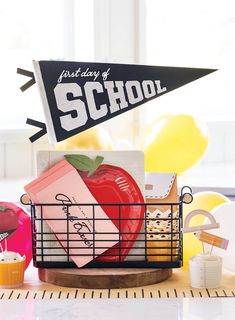 a basket filled with school supplies sitting on top of a table next to cupcakes