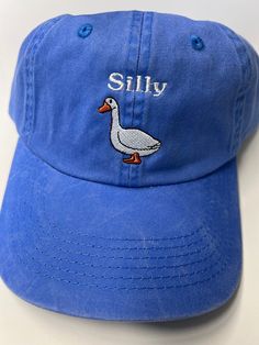 Looking for a fun and quirky accessory to add to your everyday look? Look no further than the None Silly Goose Dad Hat! Crafted from high-quality materials by trusted maker Port Authority, this washed blue hat is the perfect way to add a touch of humor to your outfit. The hat's playful design features a silly goose graphic front and center, adding an element of lighthearted fun that's sure to turn heads. With its comfortable fit and adjustable strap, this Dad Hat is perfect for any casual occasi Cheap Fun Blue Hats, Vintage Blue Adjustable Baseball Cap, Trendy Washed Baseball Cap, Vintage Adjustable Blue Baseball Cap, Trendy Washed Snapback Hat, Adjustable Blue Hats For Everyday, Trendy Washed Baseball Cap For Summer, Summer Washed Snapback Baseball Cap, Trendy Adjustable Soft-washed Hat