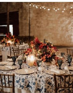 the table is set with white and blue linens, candles, and floral centerpieces