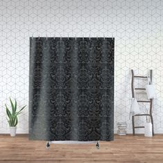 a black shower curtain hanging on a wall next to a chair and potted plant