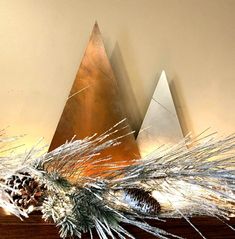 a wooden table topped with a pine cone and two metal pyramids on top of it