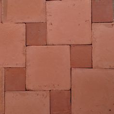 an orange cat laying on top of a red brick floor next to a white wall