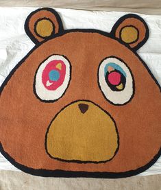 a brown bear rug with big eyes on it's face and nose is shown in front of a white sheet