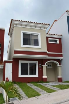 a red and white two story house with green grass in the front yard next to it