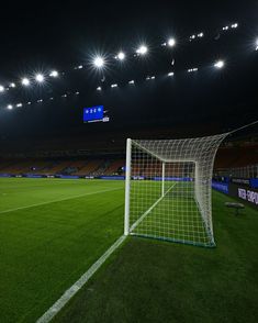 an empty soccer field at night with the lights on and one goalie's net