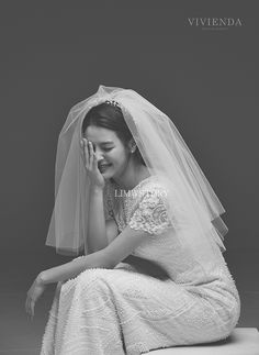 a woman in a wedding dress sitting on the ground with her hands to her face