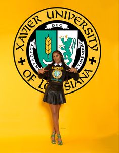 a woman standing in front of a yellow wall with the seal of university of miami on it