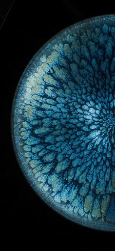 a blue bowl with an intricate design in the center on a black table top, viewed from above