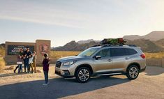 people standing in front of a silver subarunt parked on the side of a road